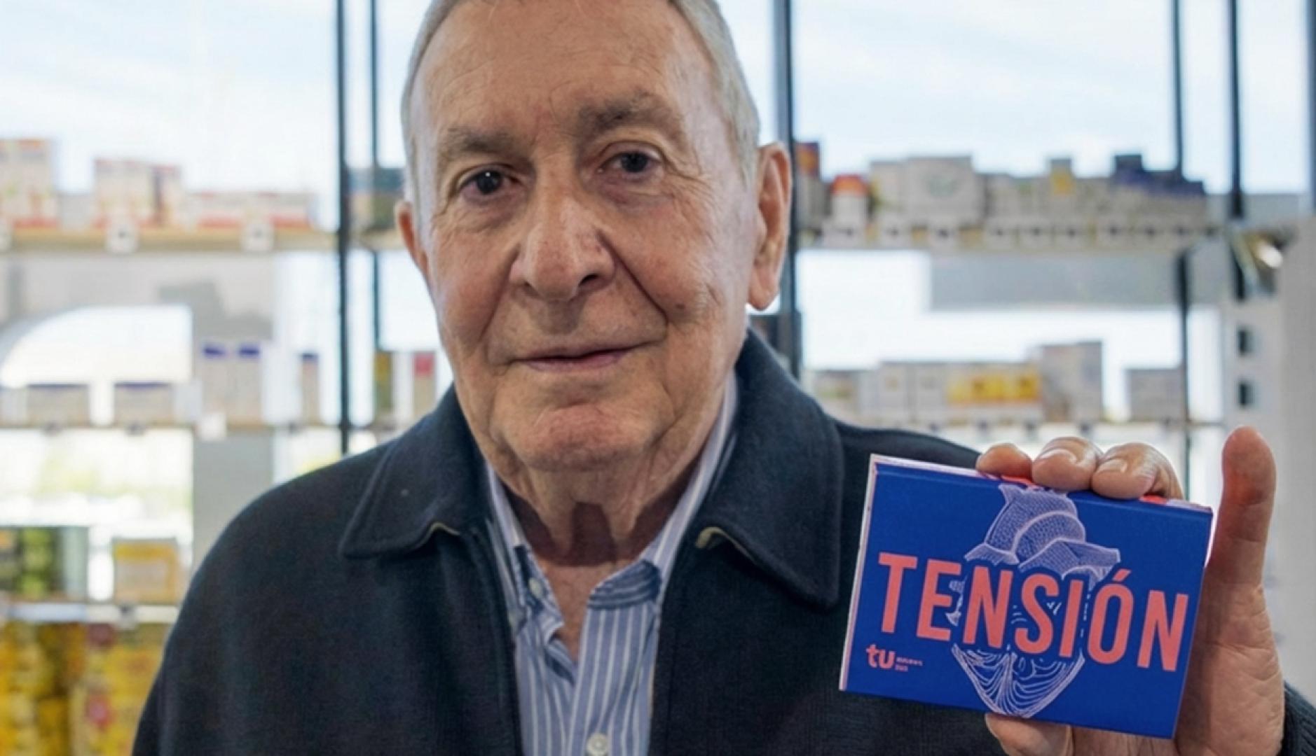 Un hombre mayor muestra una caja de pastillas en la que se lee en grande "Tensión"