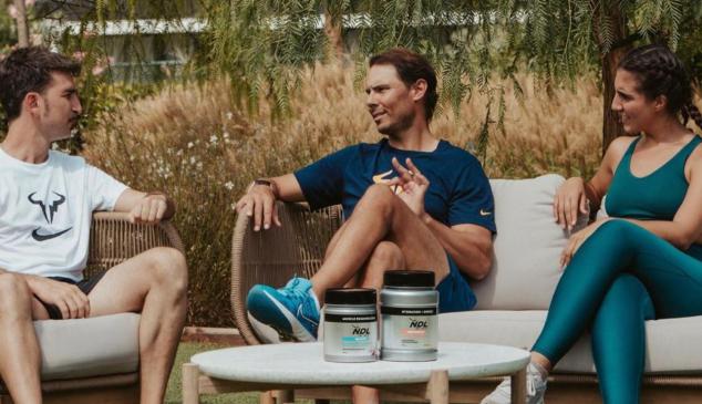 rafa nadal sentado charlando frente a una mesa con los suplementos alimenticios de su marca