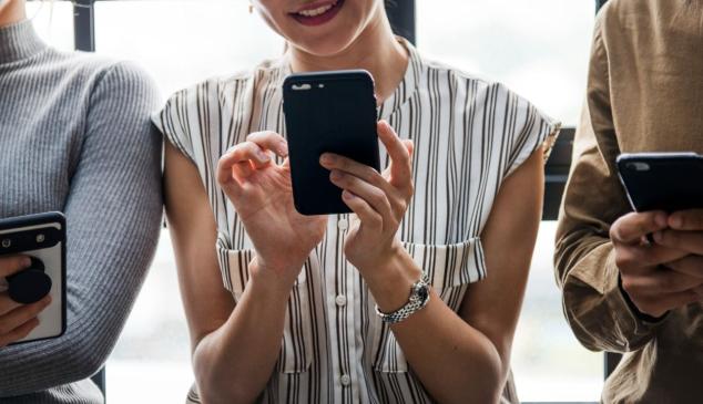 Tres personas jóvenes mirando sus teléfonos móviles