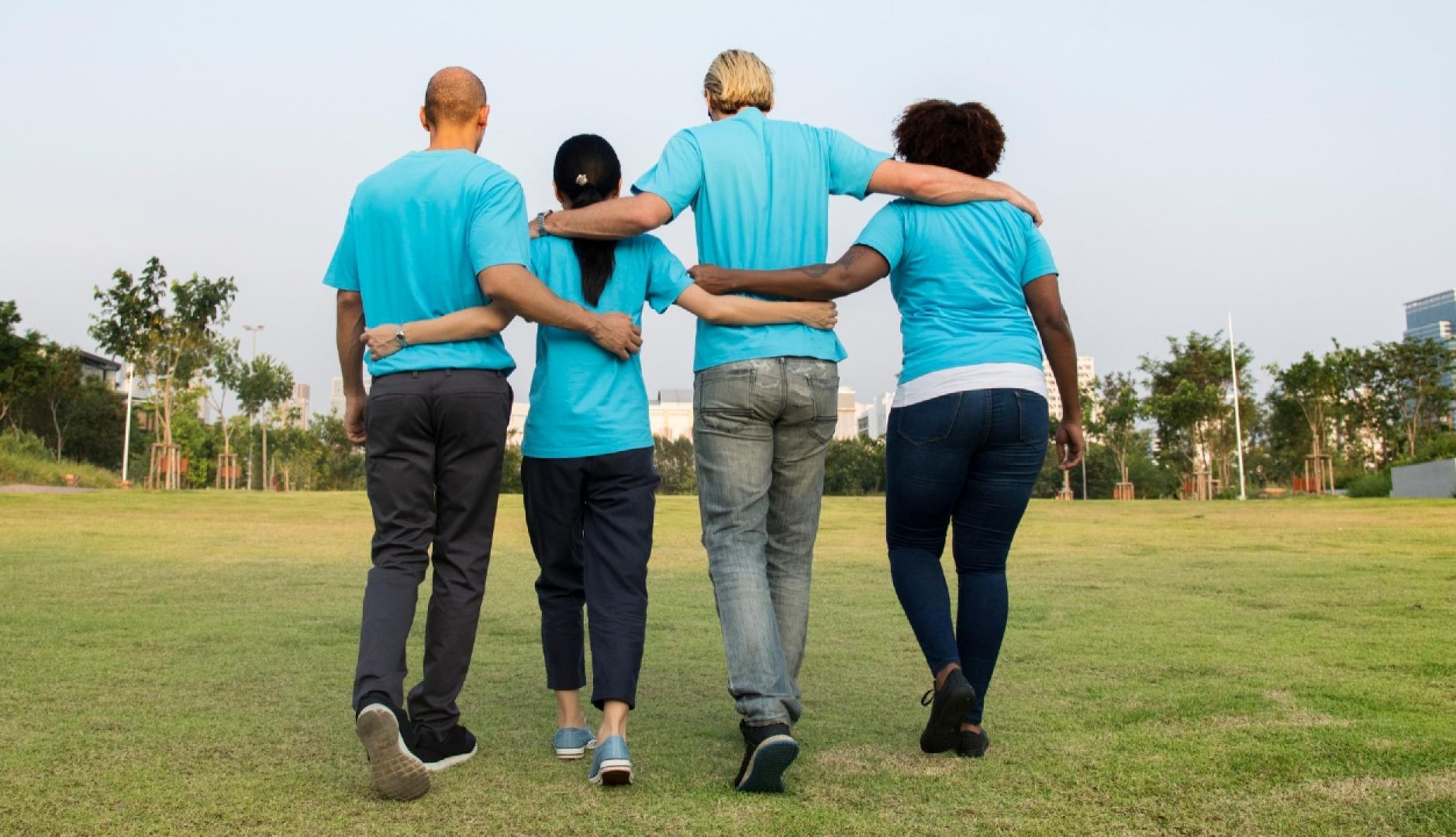 Un equipo de espaldas se abraza, vestidos todos con polos azules