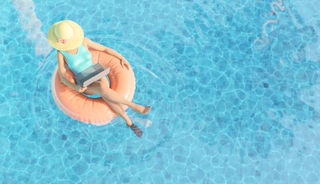 Mujer trabajando en verano sobre un flotador en la piscina