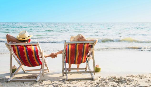 Dos personas sentadas en hamacas en la orilla del mar