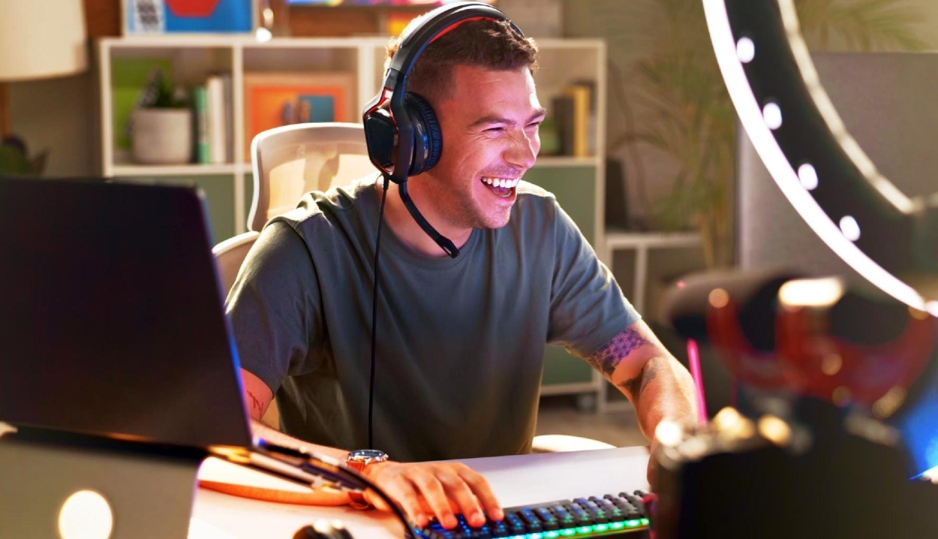 Un chico youtuber riendo con los cascos puestos frente al ordenador