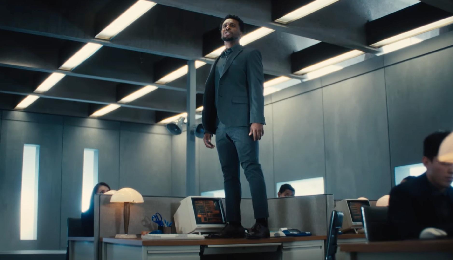 Un hombre de pie sobre un escritorio en una oficina gris