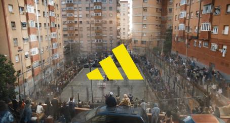 El logo de Adidas en amarillo sobre una cancha callejera rodeada de gente