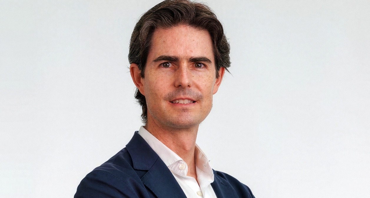 Un primer plano de Alejandro Guerra vestido con traje azul y camisa blanca