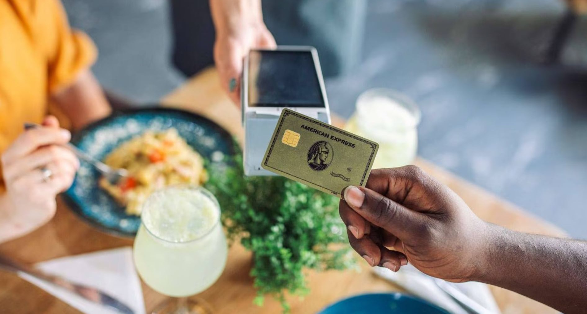 Persona pagando en un datáfono con una tarjeta de American Express