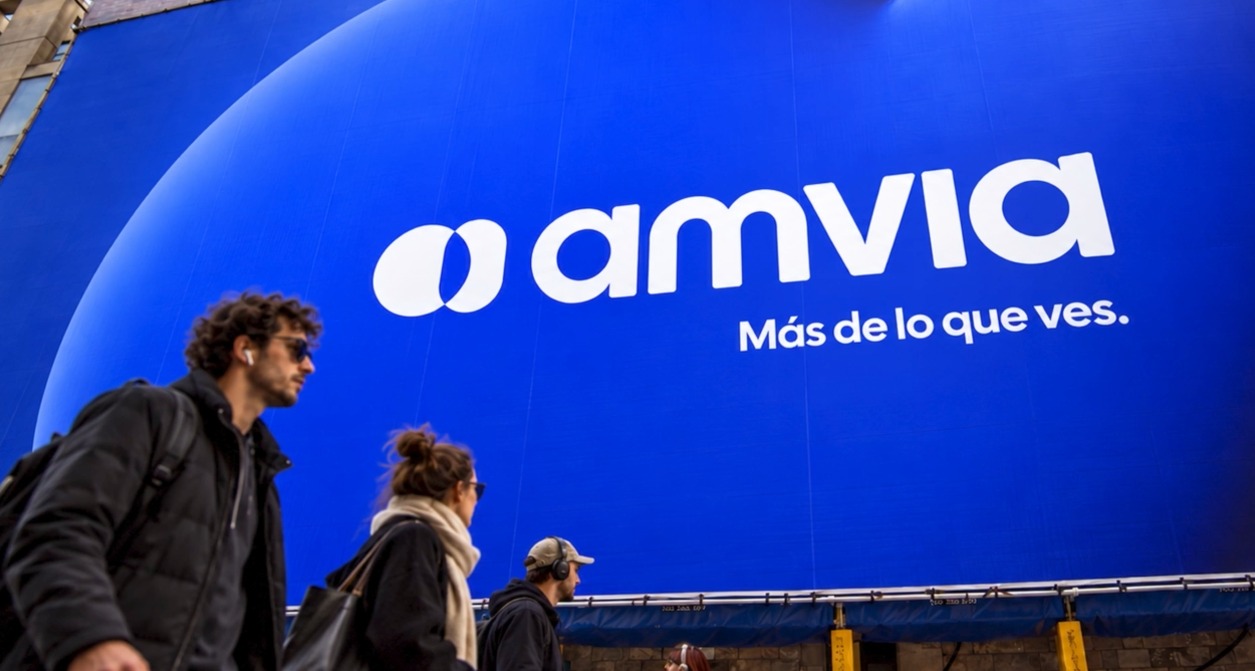 Personas caminando en la calle frente a una lona con el logotipo de Amvia