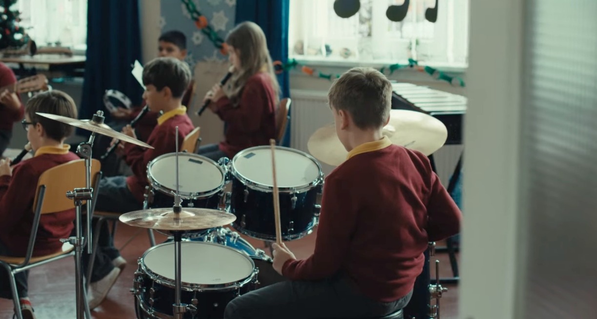 Un niño tocando la batería en una orquesta escolar