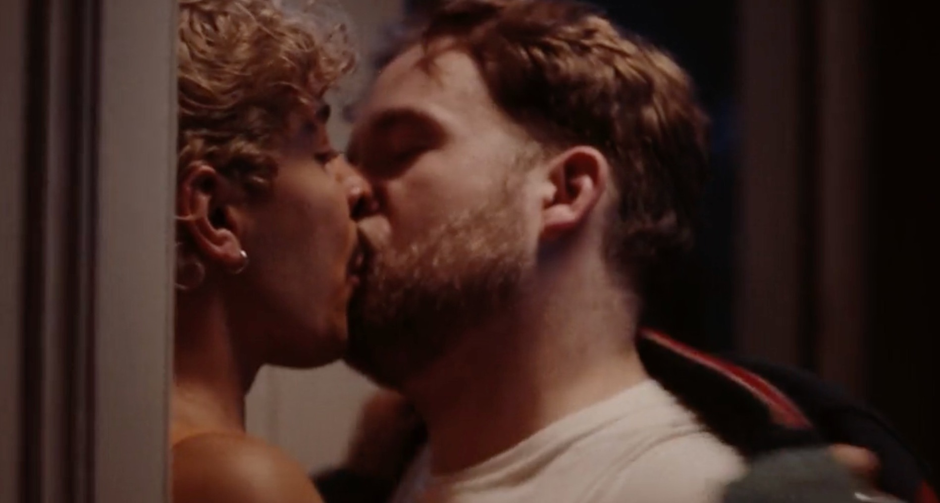 Dos hombres jóvenes besándose