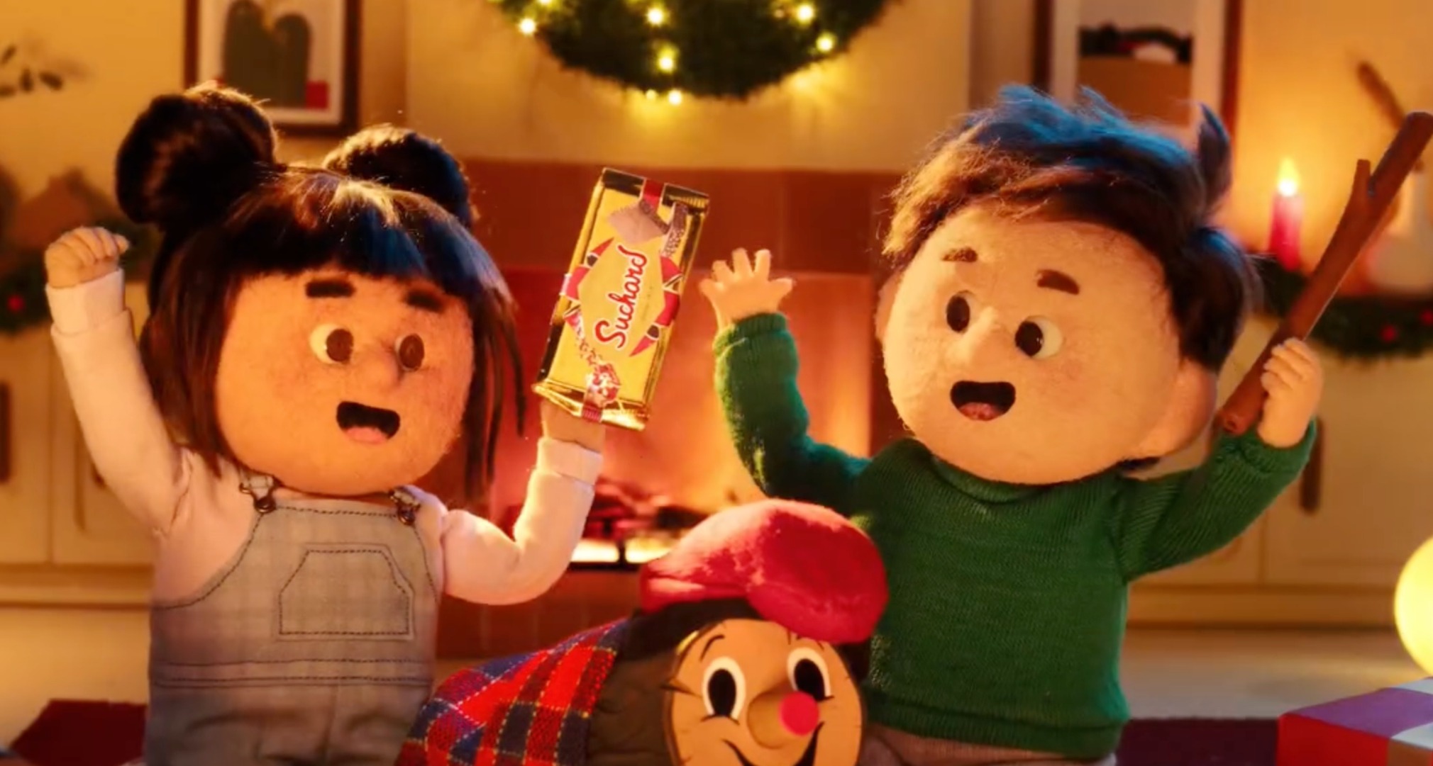 Dos niños celebrando la Navidad con una tableta de Suchard en la mano