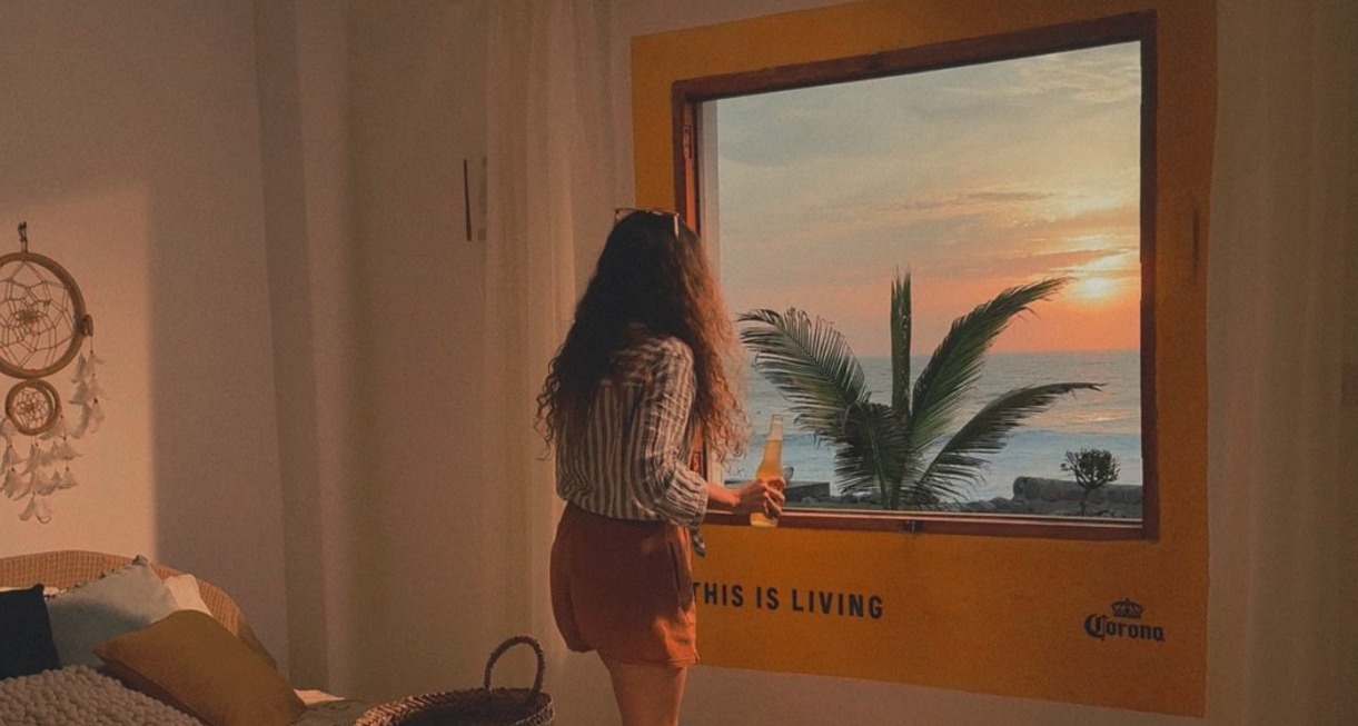 Corona quiere patrocinar los mejores atardeceres desde un local o un Airbnb chica viendo un atardecer por la ventana