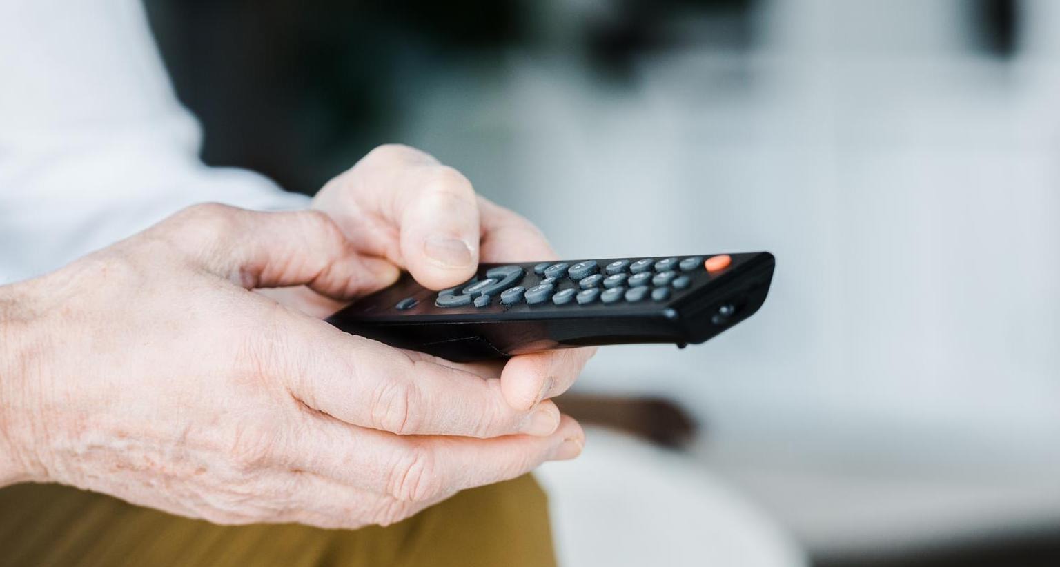 Manos sujetando un mando a distancia de televisión