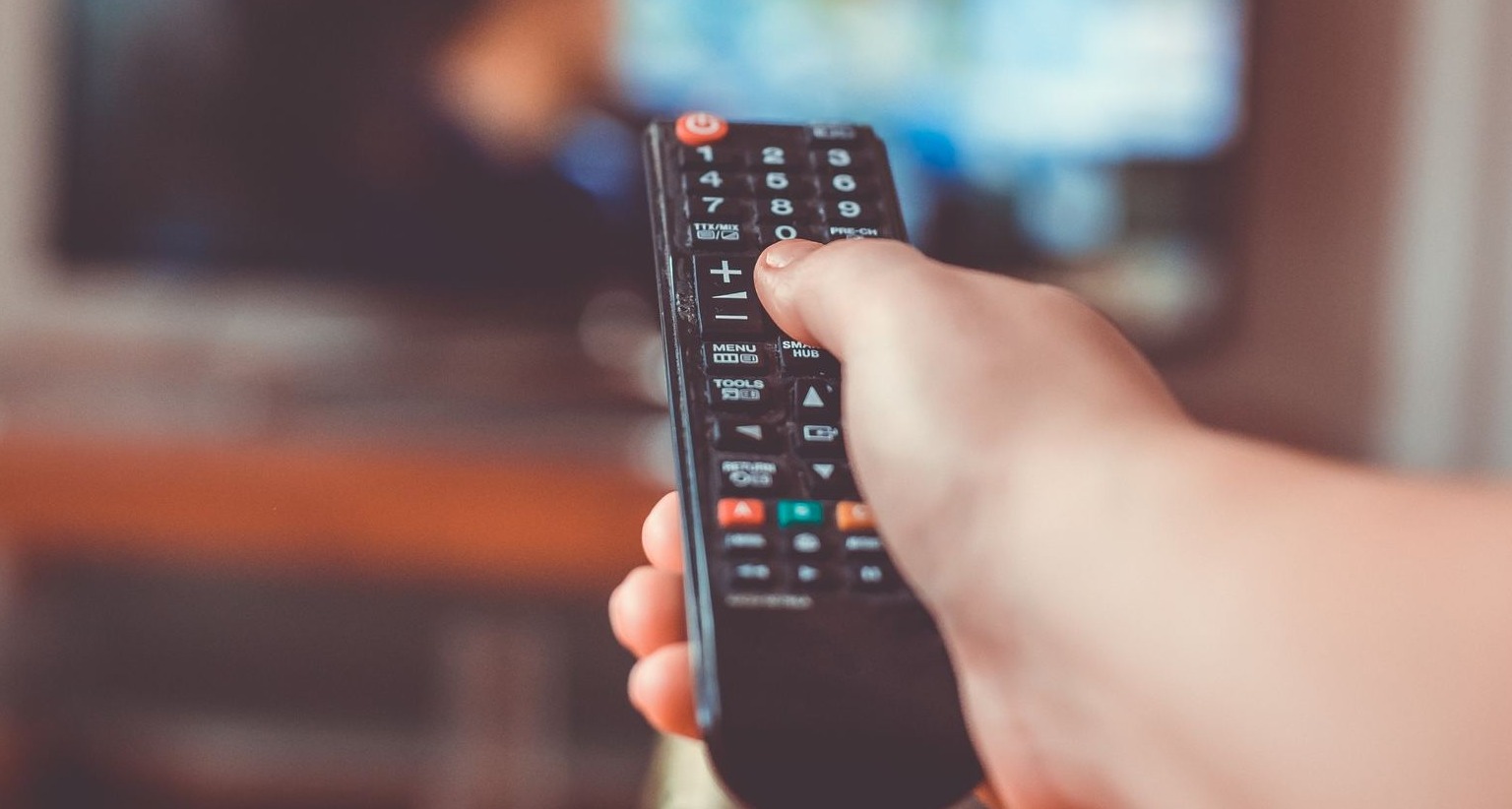 Mano sosteniendo un mando de televisión a distancia