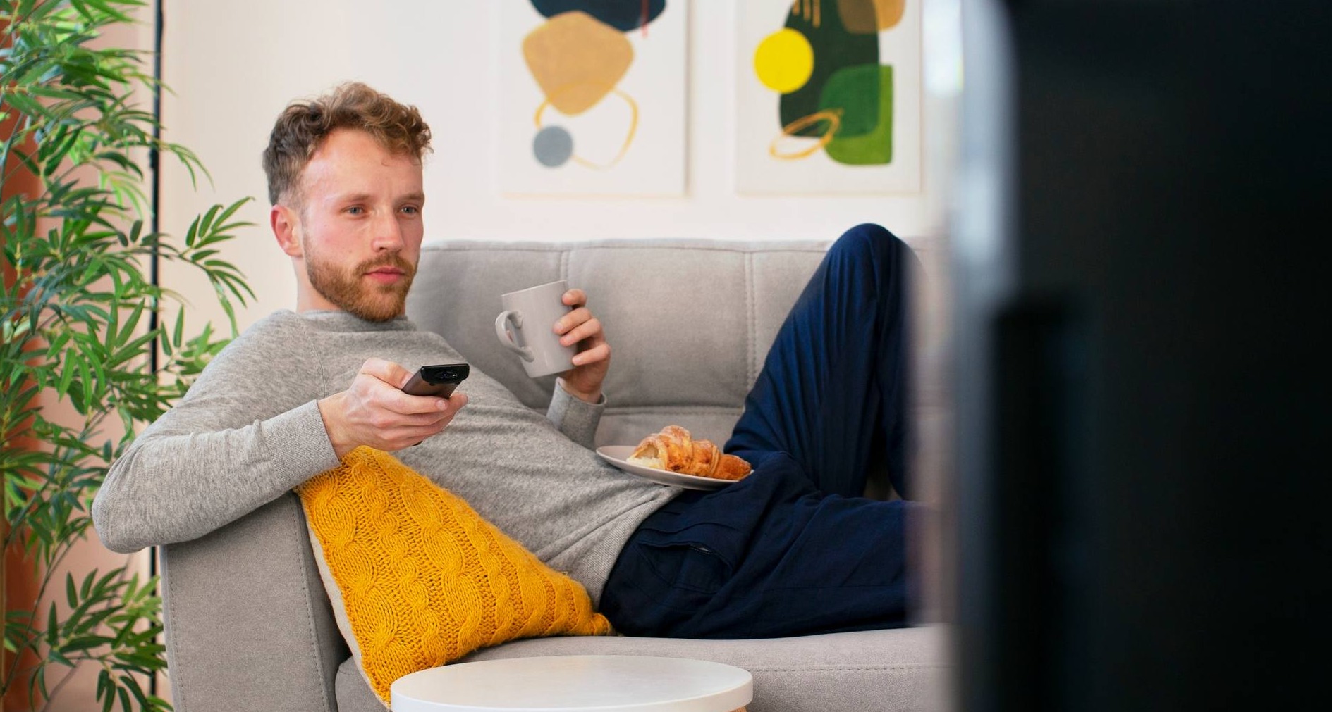 Hombre viendo la televisión tumbado en el sofá