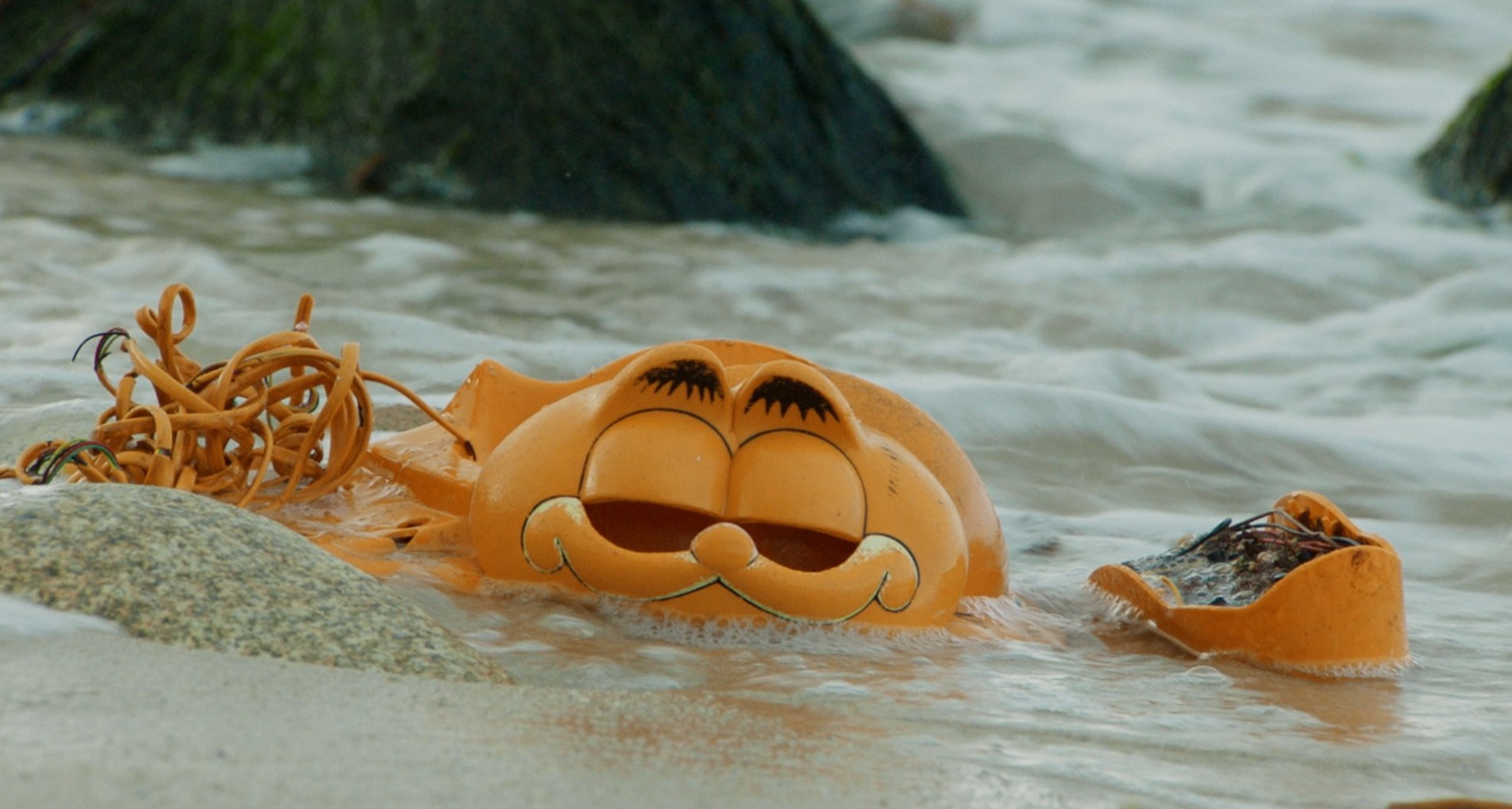 Partes de un teléfono con forma de Garfield en la playa