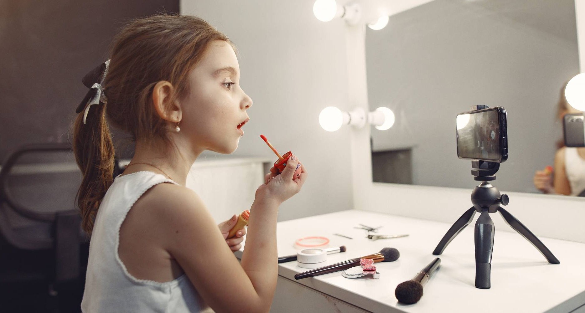 La tendencia de belleza entre la Generación Alpha da forma a los compromisos de las marcas cosméticas Niña maquillándose y grabándose con el móvil