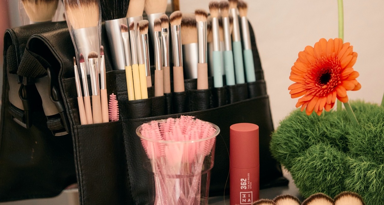 Un set de brochas de maquillaje junto a una flor naranja