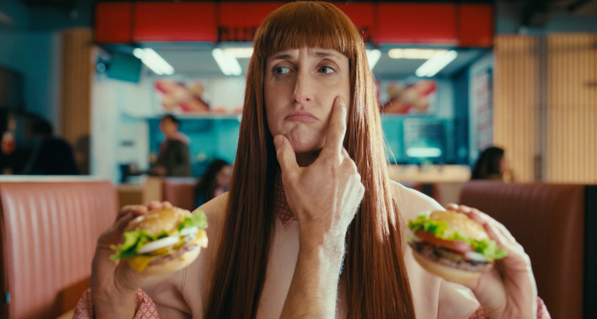 Una mujer sostiene una hamburguesa mini en cada mano