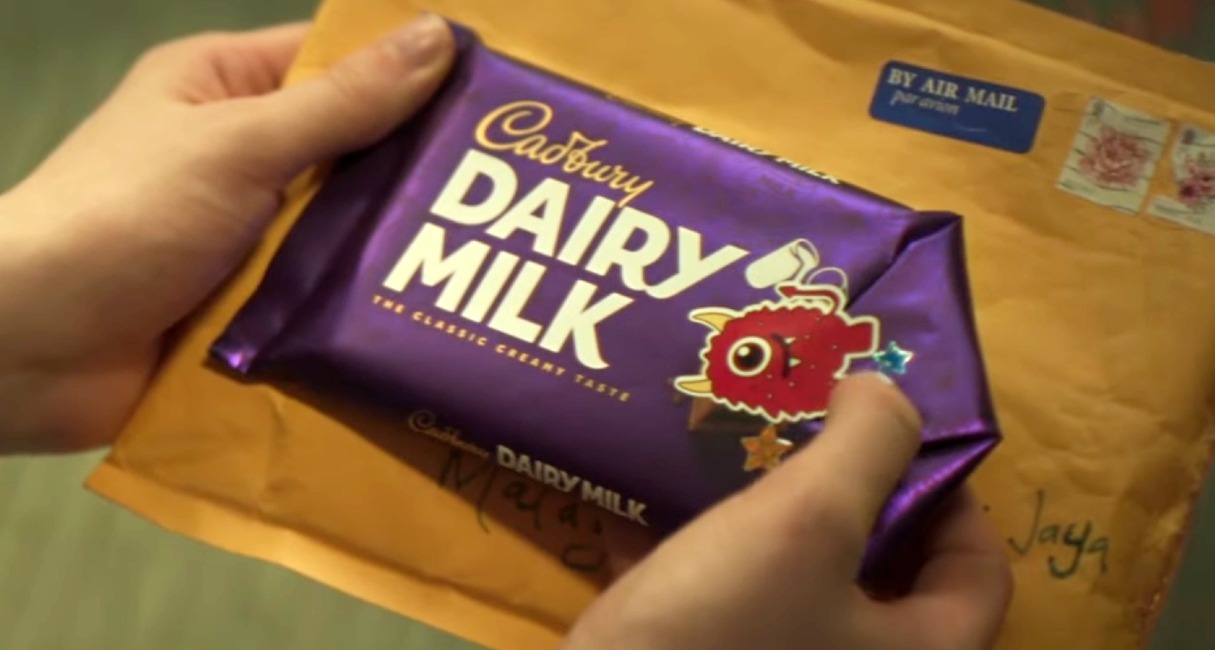 Unas manos que sostienen la tableta de Cadbury usada y cerrada con una pegatina