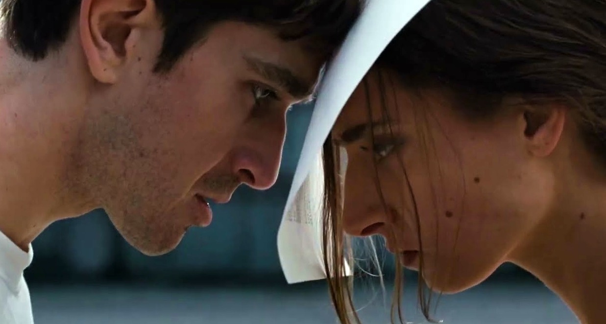 Un hombre y una mujer juntando la frente con un folio de papel entre ambos