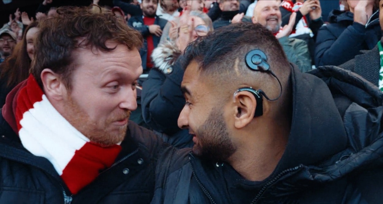 Dos aficionados se miran en el estadio, uno de ellos lleva un audífono