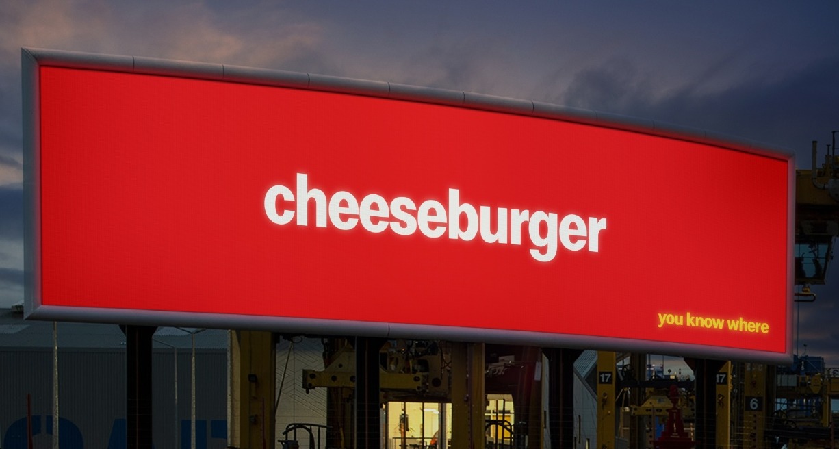 Una valla de publicidad con fondo rojo y escrito cheeseburger en blanco