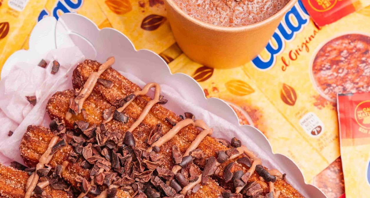 Un bodegón de churros con un vaso de ColaCao