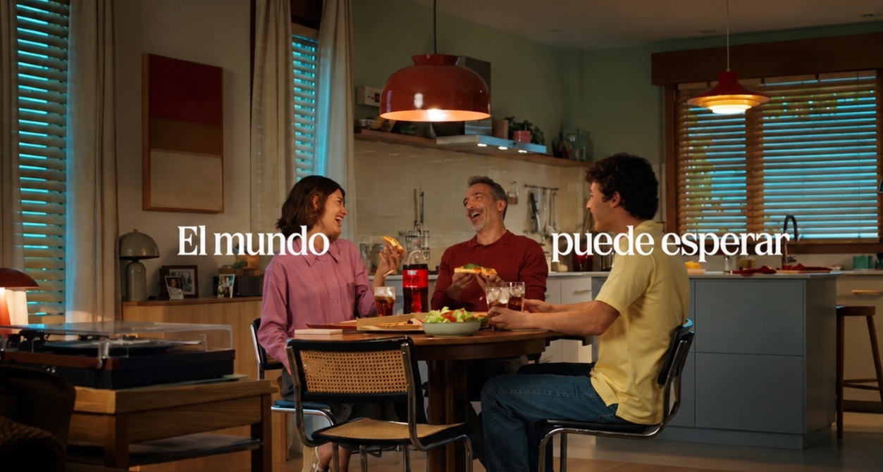 Un padre y sus dos hijos sentados a la mesa comiendo pizza y riendo
