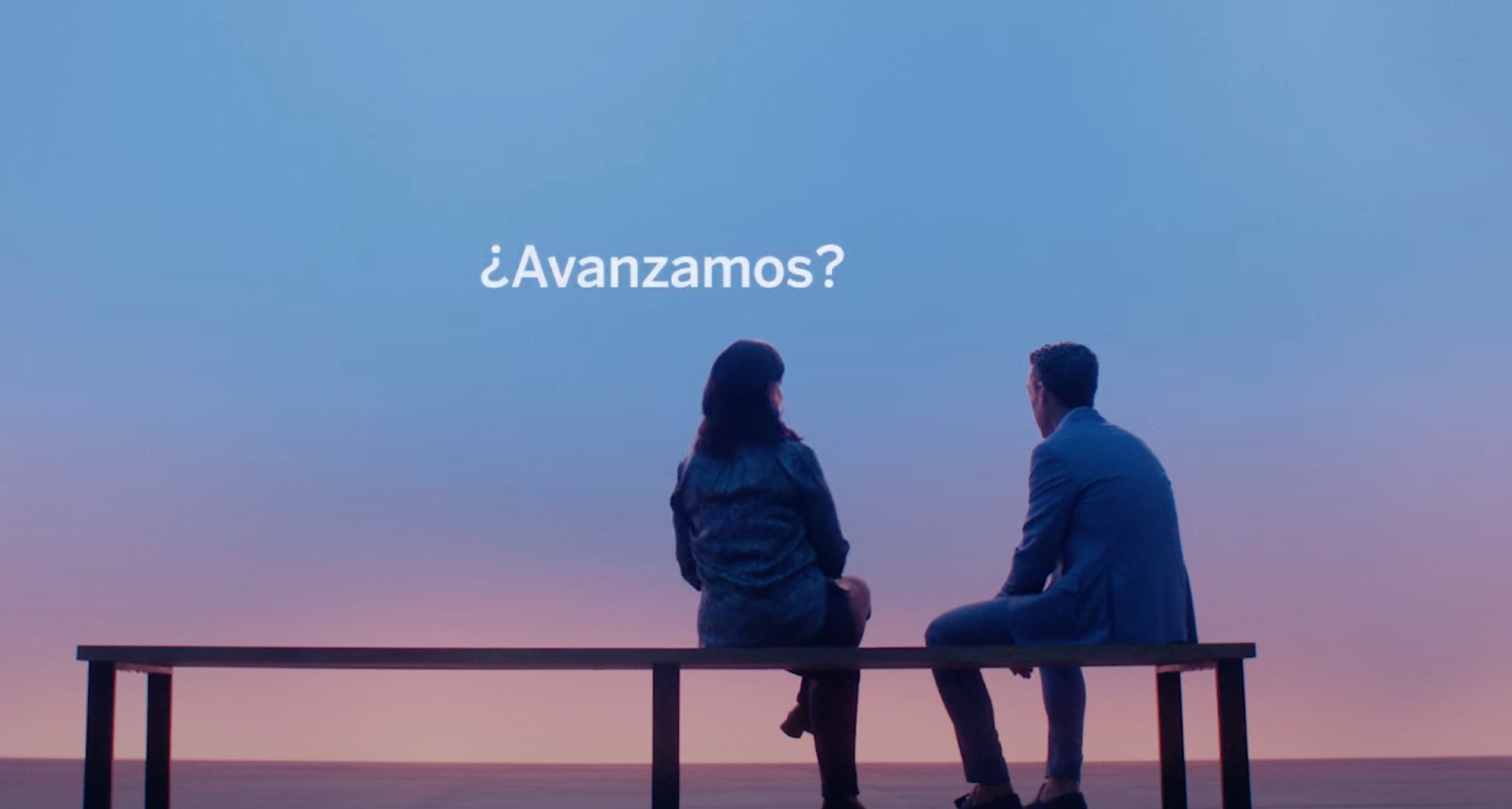 Imagen de dos personas sentadas en un banco con fondo azul