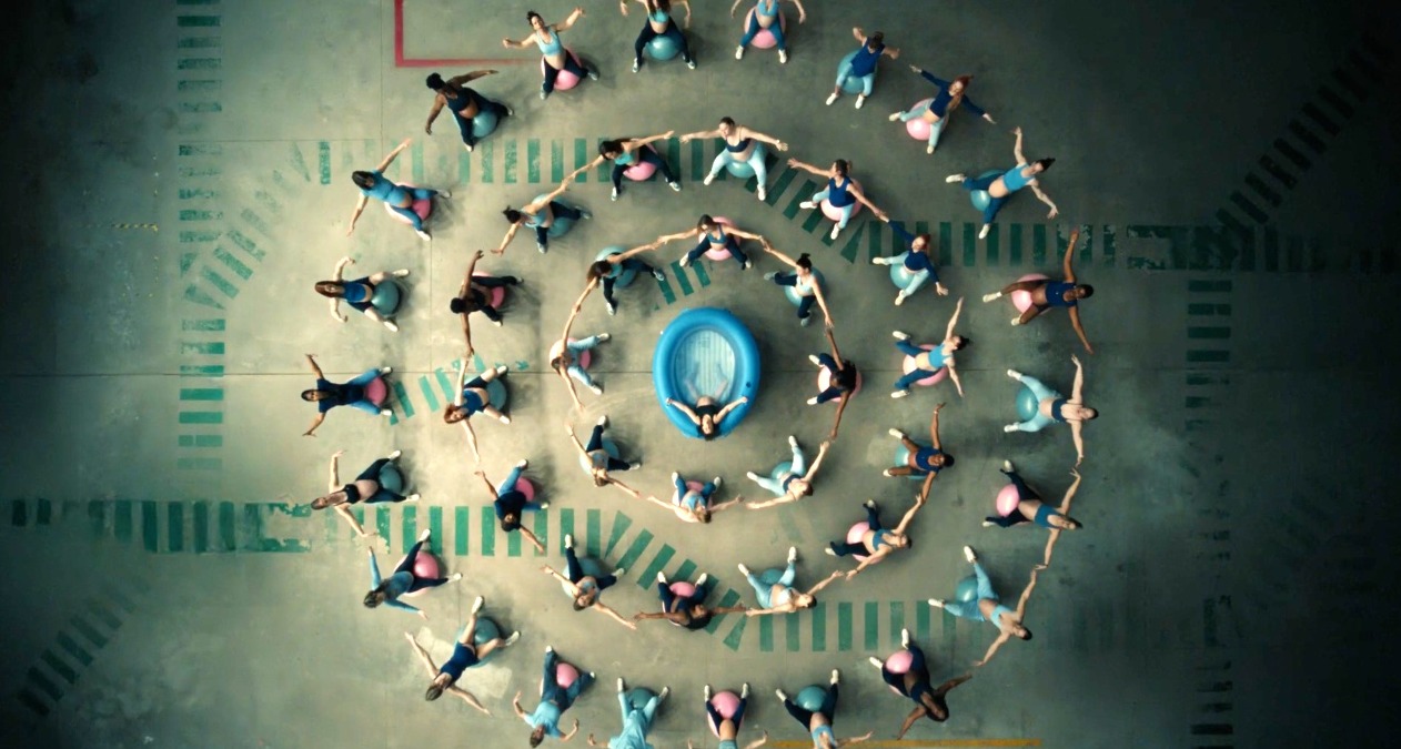 Un círculo de mujeres sobre pelotas de pilates alrededor de una piscina hinchable