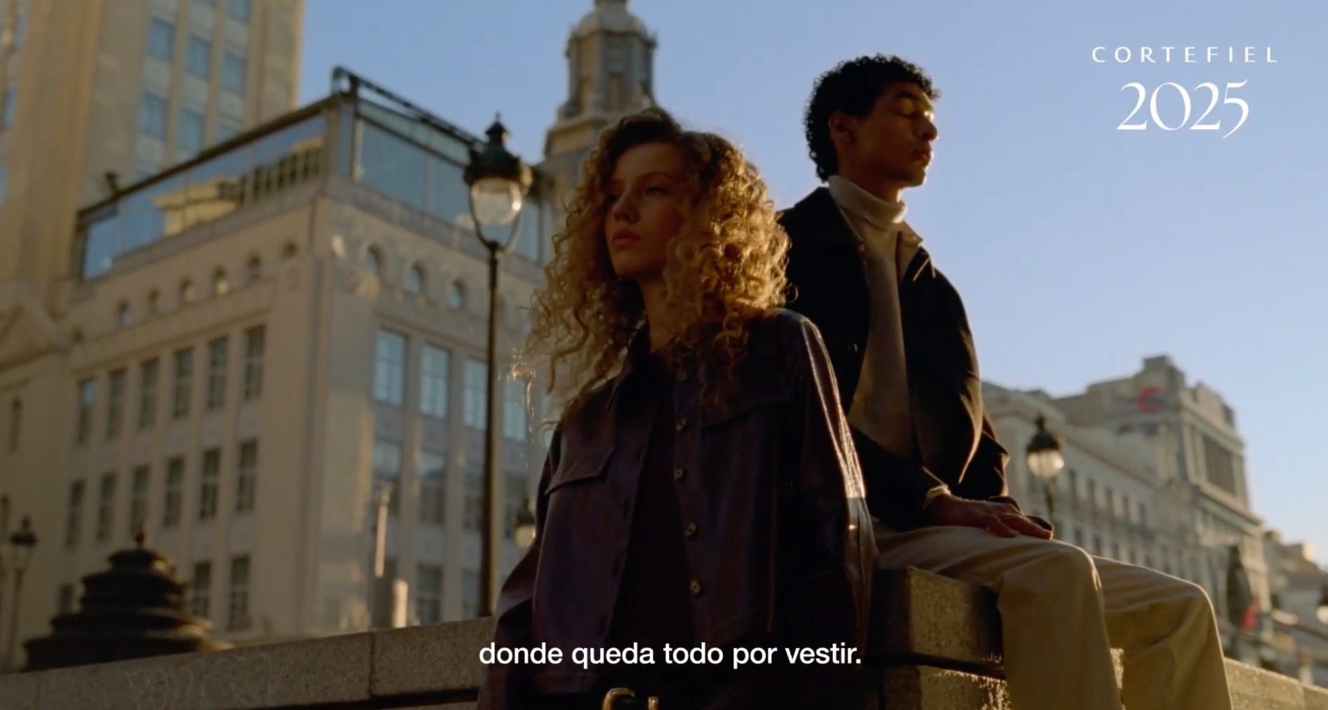 Dos jovenes ante edificios de la Gran Vía de Madrid en un annuncio de Cortefiel