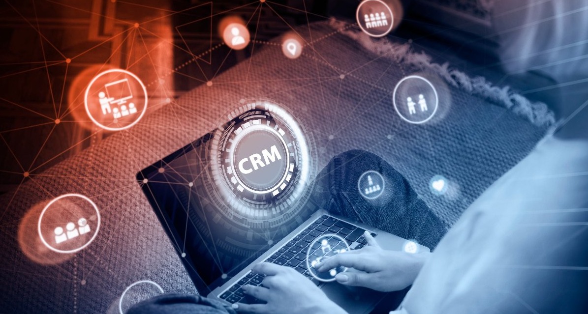 La Inteligencia Artificial como impulsora del aumento de conversiones y ventas a través de la automatización una persona tecleando un ordenador y las siglas CRM sobreimpresas