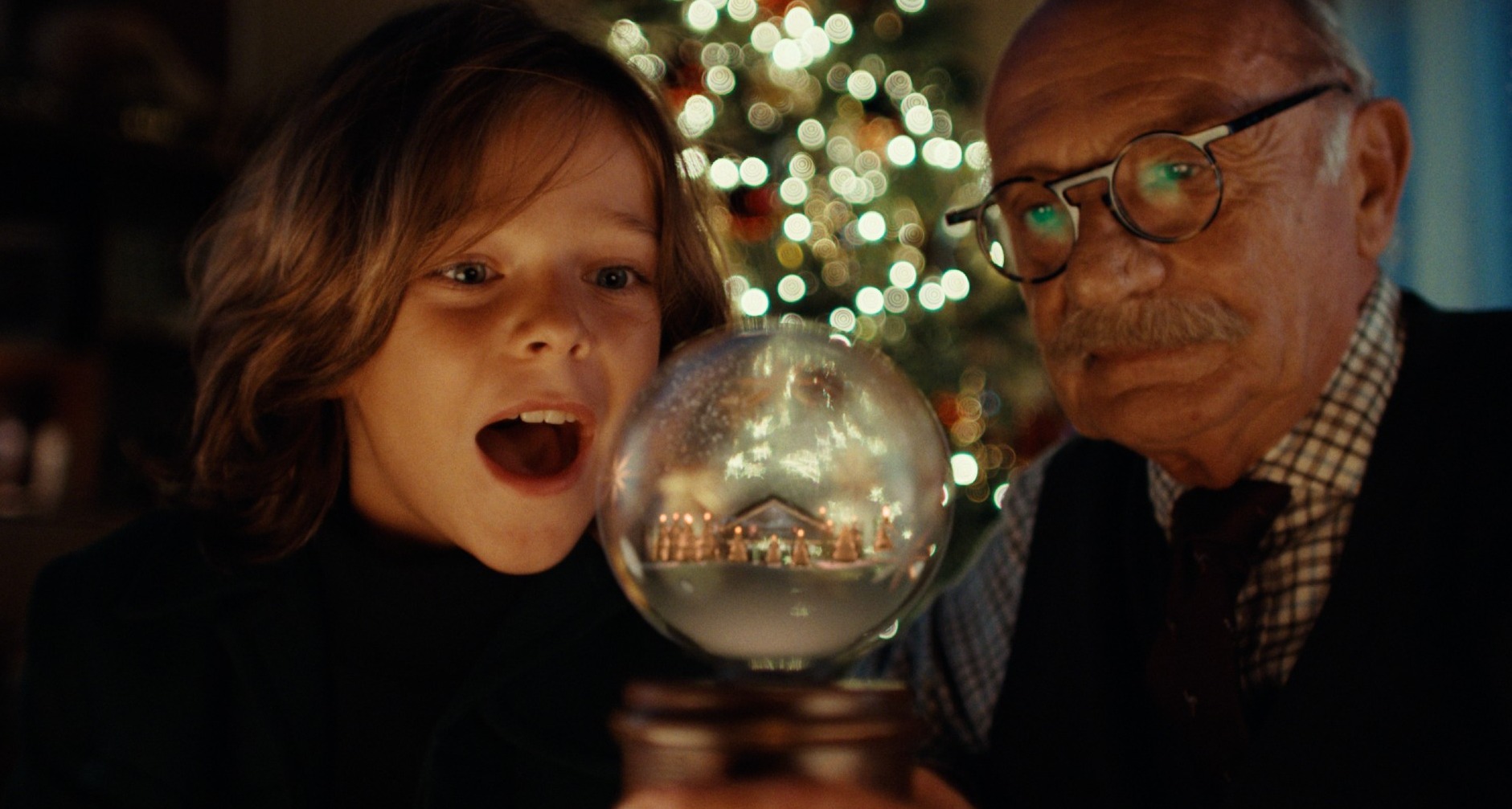Un abuelo y su nievo miran una bola de Navidad