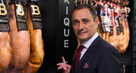 Enrique Tomás junto a unos jamones colgados en la tienda