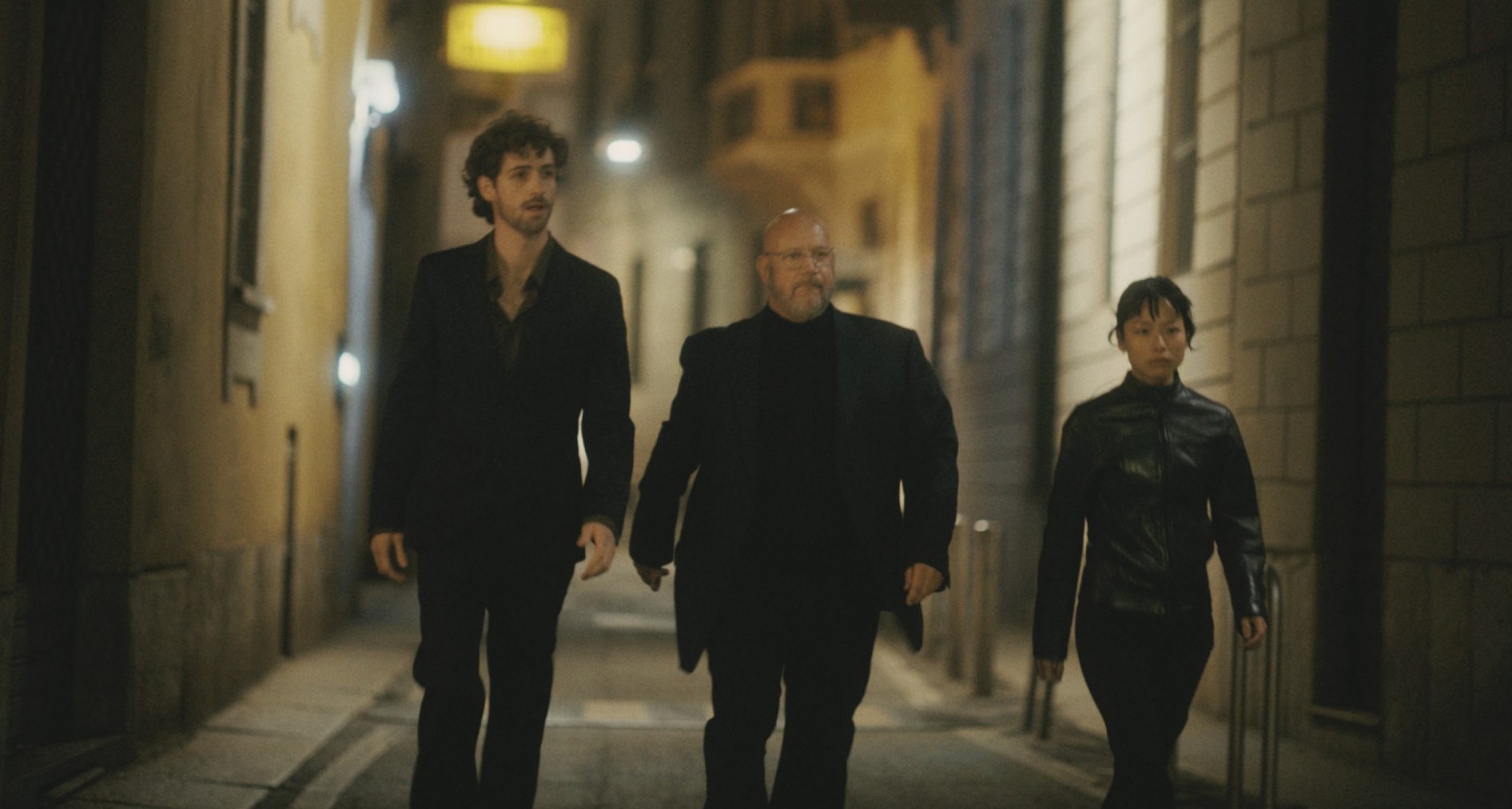 Tres personas vestidas de negro andando por la calle de noche