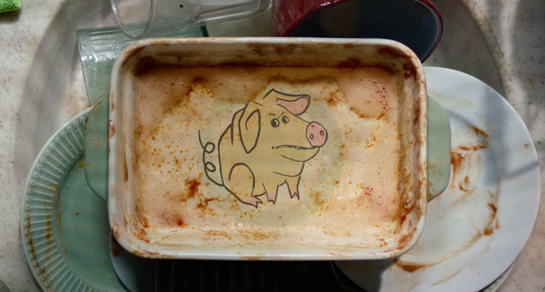 Fuente de cocina con un grabado de un cerdo a remojo en el fregadero