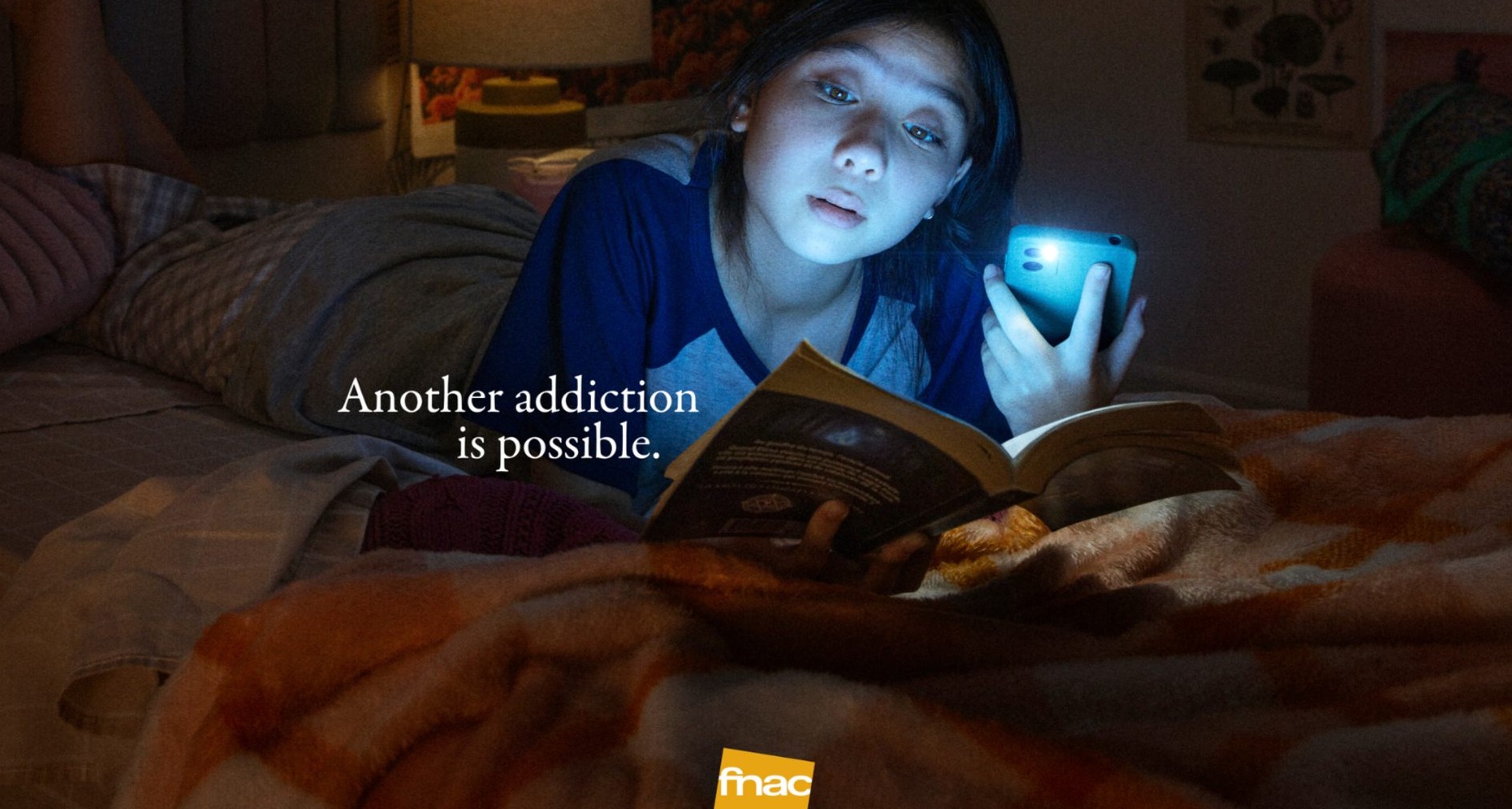 Joven lee un libro iluminado con la linterna del teléfono