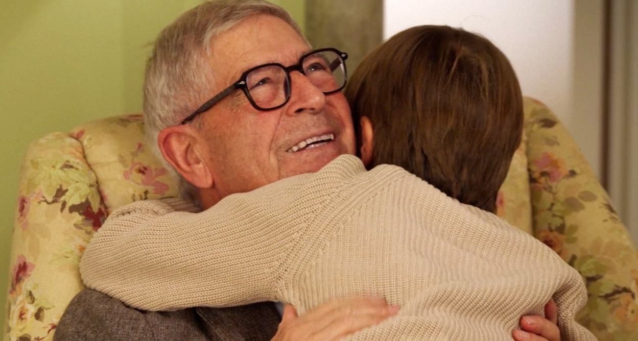 Un abuelo abrazando a su nieto pequeño en el sillón