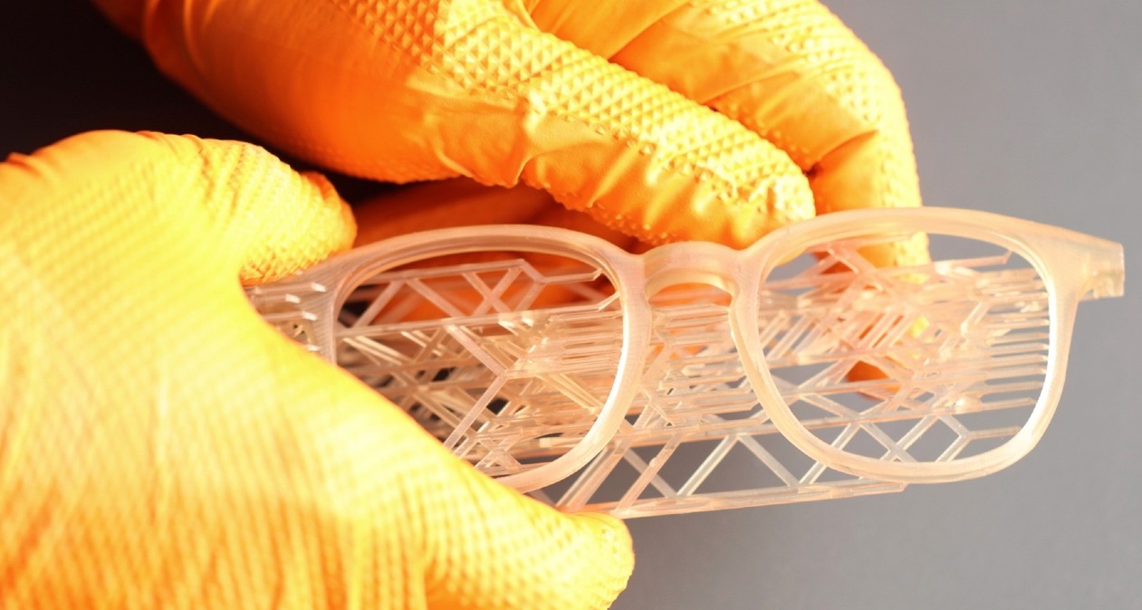 Unas manos con guantes sosteniendo unas gafas hechas en 3D