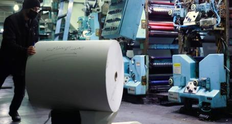 Hombre mueve rollo de papel en una imprenta