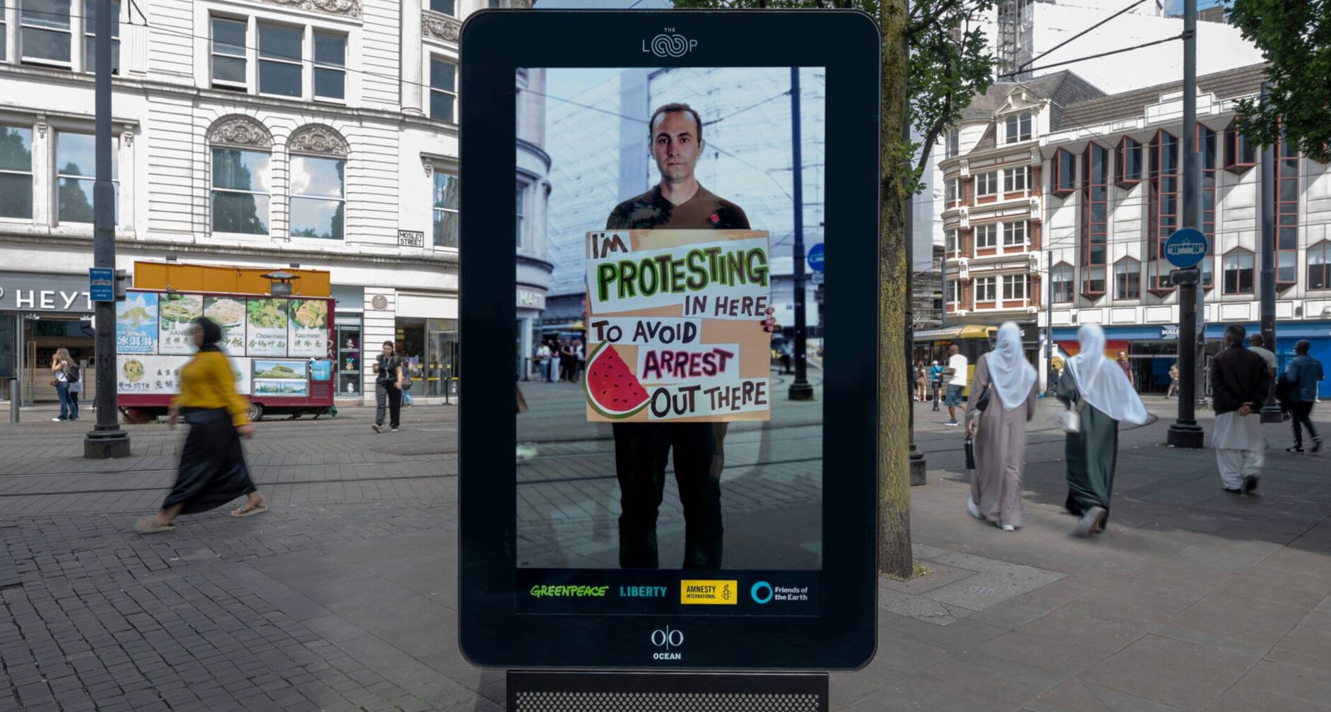 Greenpeace Reino Unido pone la publicidad exterior digital al servicio del derecho a protestar Persona sujetando una pancarta en un mupi digital
