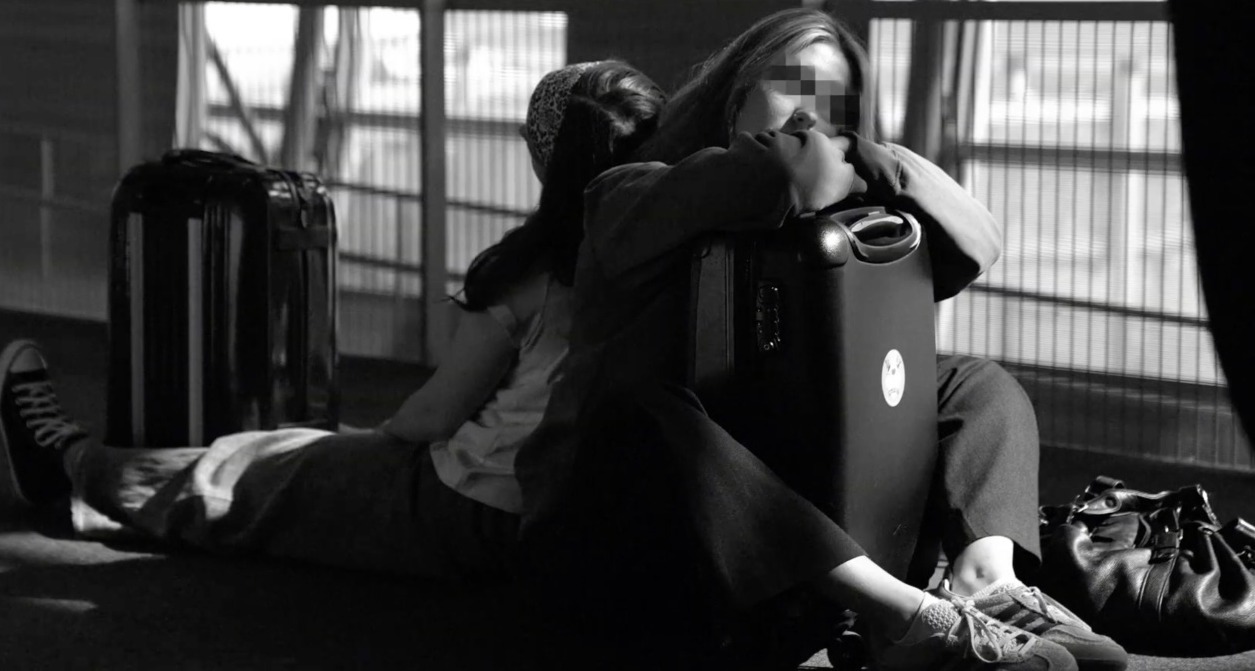 dos chicas durmiendo en el suelo del aeropuerto con las maletas