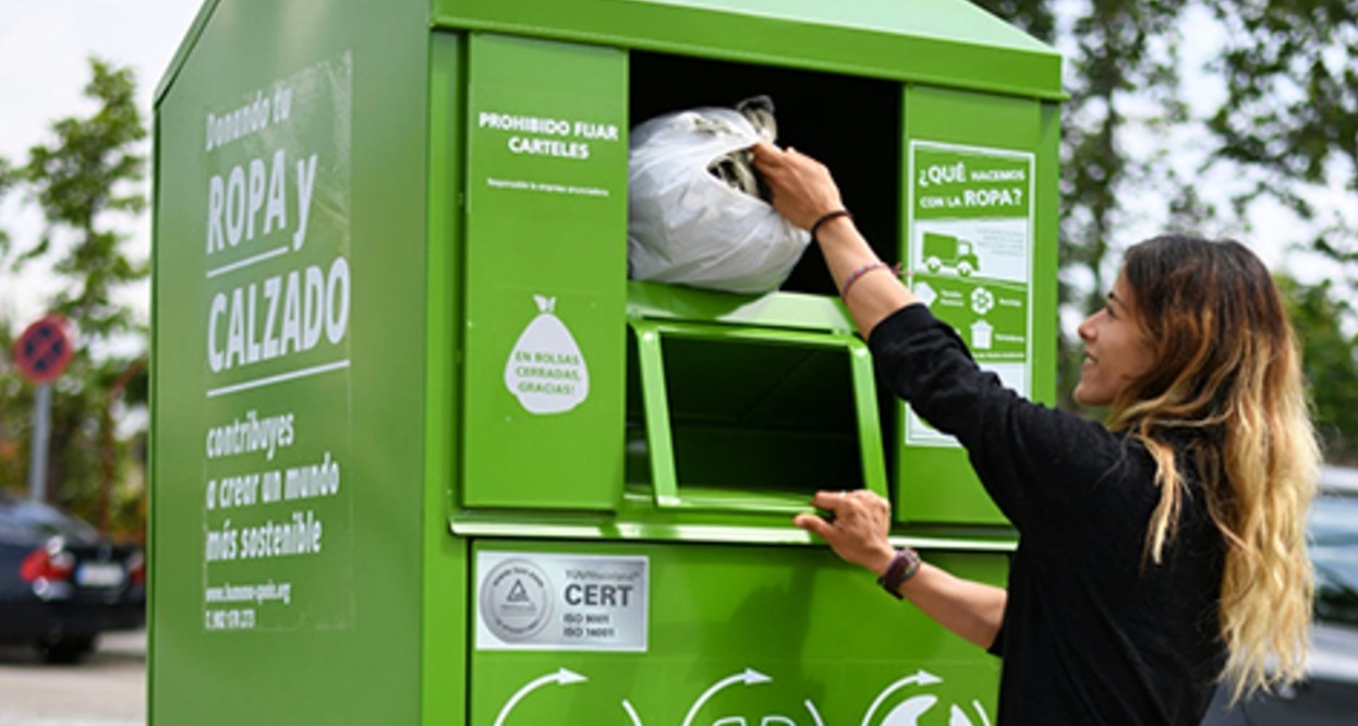 Una mujer depositando una bolsa de ropa en un contenedor de Humana