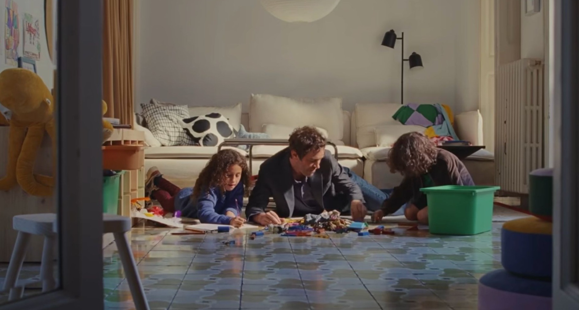 Un hombre juega con sus hijos en el salón de casa