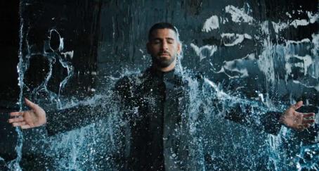 Ilia Topuria con los brazos en cruz bajo una cortina de agua vestido