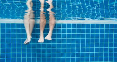Piernas de dos personas sumergidas en una piscina