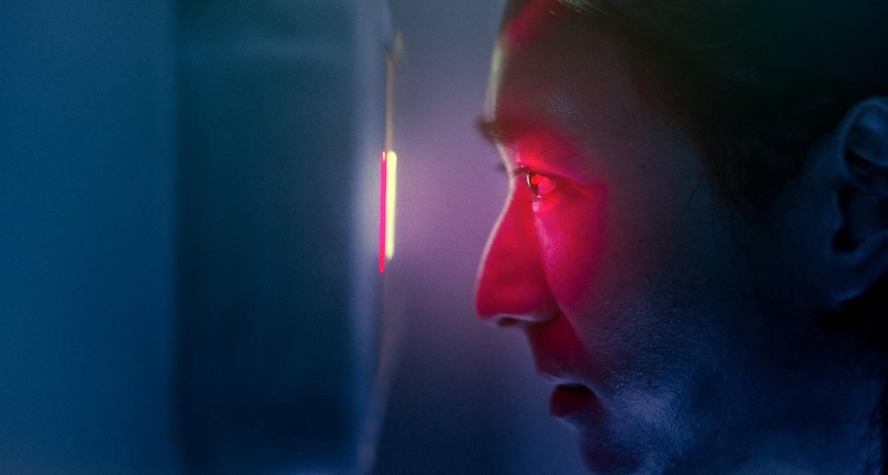 Un hombre mirando por una mirilla digital con luz roja