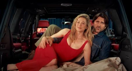 Una pareja tumbada dentro del maletero del coche abrazándose en pose sexy