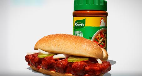 El chef Joshua Weissman y el creador de contenido gastronómico Kevin Novarpar en una cocina preparando un sándwich de costillas con la salsa Knorr.